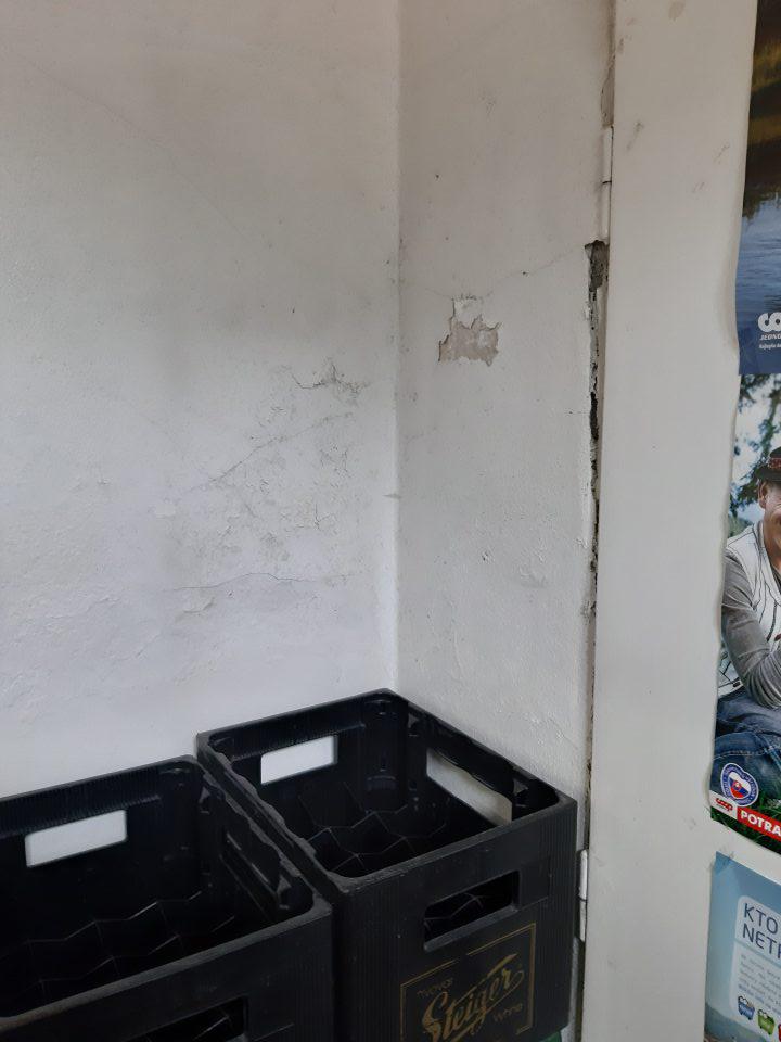 Stena v manipulačnej chodbe pri dverách poškodená, omietka opadaná.