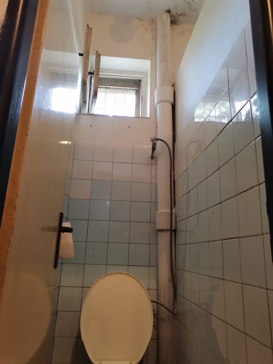 Stena v záchode v okolí rúry je znečistená, omietka poškodená, opadaná, povrchový náter odtokovej rúry je poškodený.