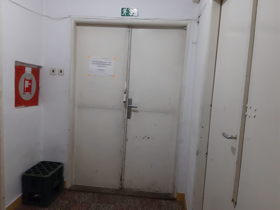 Stena v manipulačnej chodbe určenej na dočasne uskladnenie pečiva je po obvode poškodená, omietka opadaná - dvere príjmové, dvere v manipulačnej miestnosti majú poškodený, opotrebovaný náter.