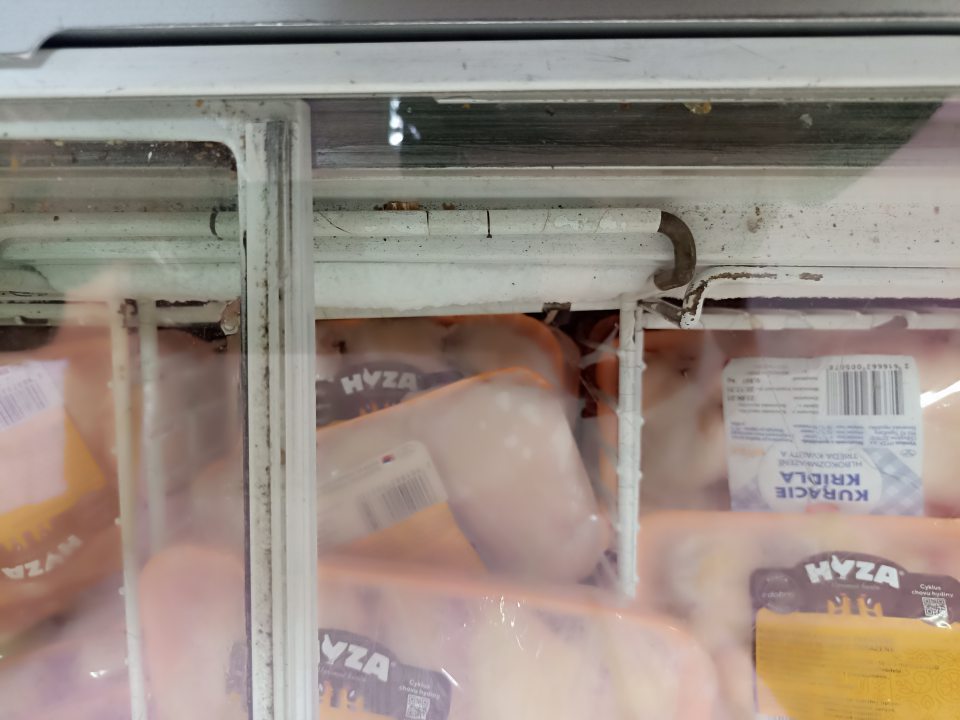 Mriežkované koše mraziaceho zariadenia na hlbokozmrazené potraviny (hydina) na predajni s poškodeným, poodlupovaným náterom, miestami s hrdzavým povrchom a lišty posuvných dvier boli znečistené nahromadenými nečistotami a zvyškami potravín.