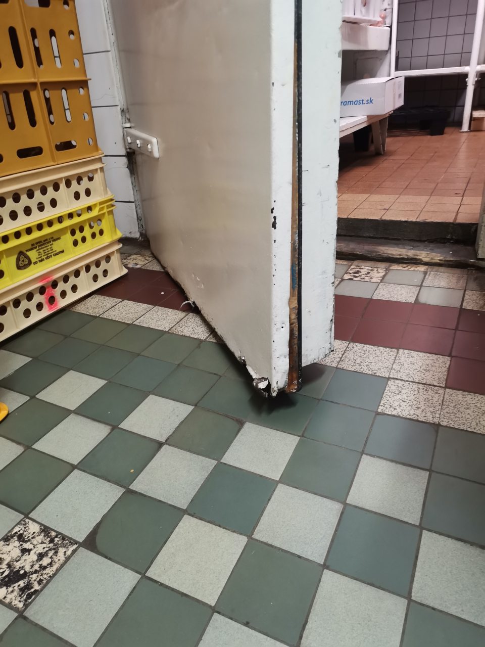 - Dvere do chladiaceho boxu v zázemí prevádzky sú v spodnej časti poškodené, povrchové kovové prekrytie dverí je uvoľnené