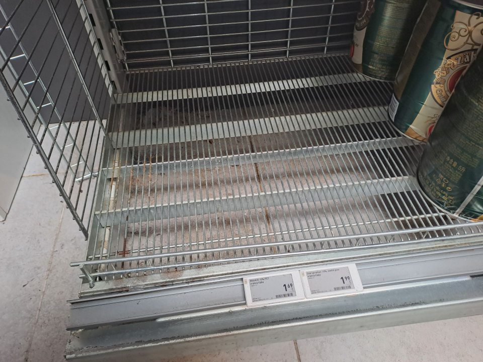 Znečistená podlaha pod regálom s ponukou piva.
