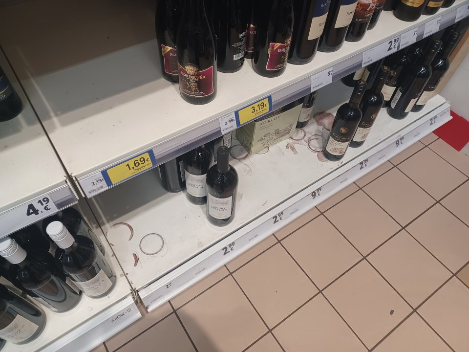 Znečistené police regálov v mieste ponuky alkoholu na viacerých miestach.