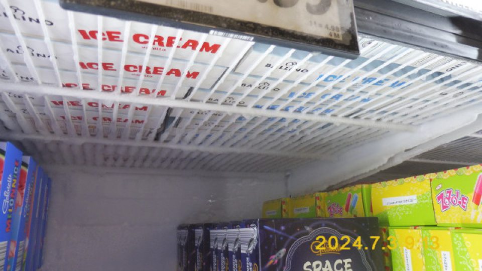 V mraziacom zariadení mriežky, zadný panel a výrobky (mrazené krémy) pokryté námrazou a kvapkami zamrznutého kondenzu.