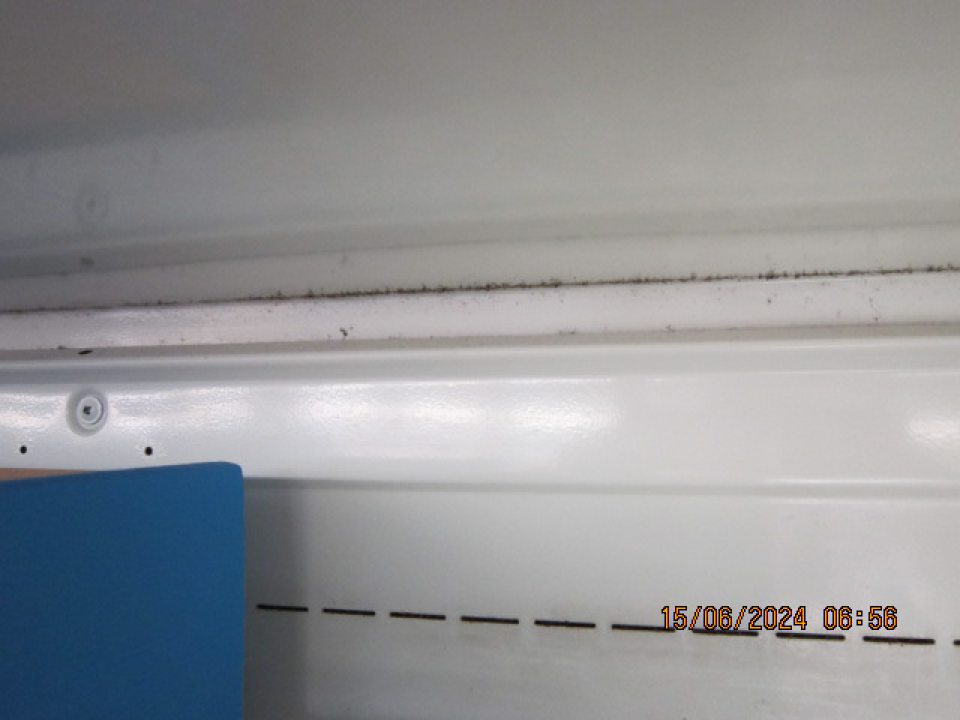 Znečistená zadná stena chladiacej vitríny určenej na predaj mliečnych výrobkov.