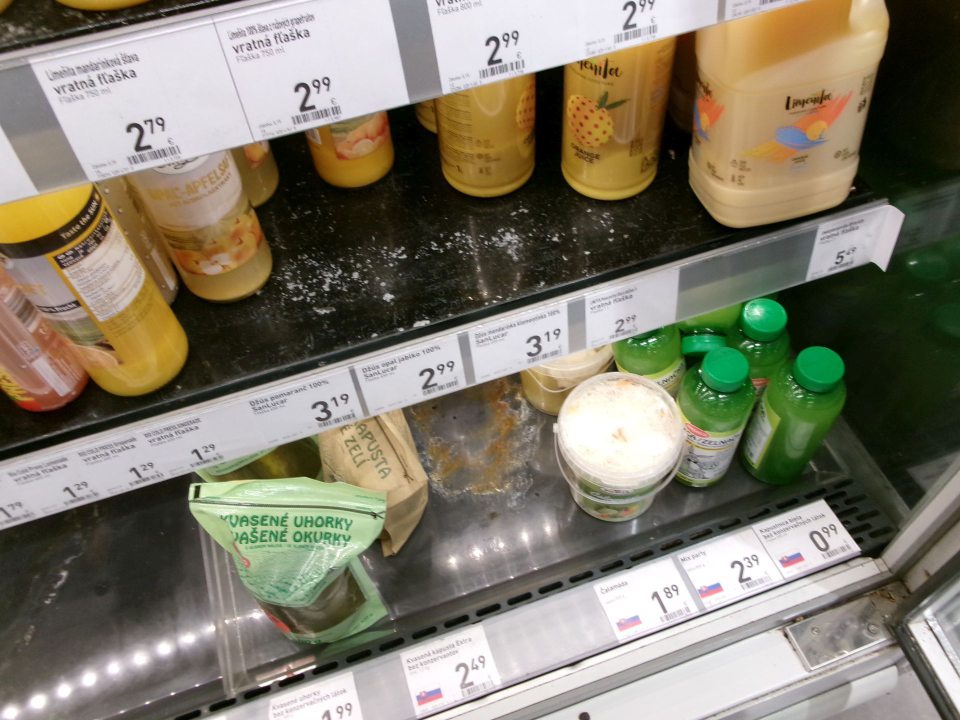 opotrebovaný a skorodovaný regál na predajnej ploche s uloženými sterilizovanými výrobkami - olupujúci sa náter police v chladiarenskej vitríne s uloženámi potravinárskymi výrobkami 