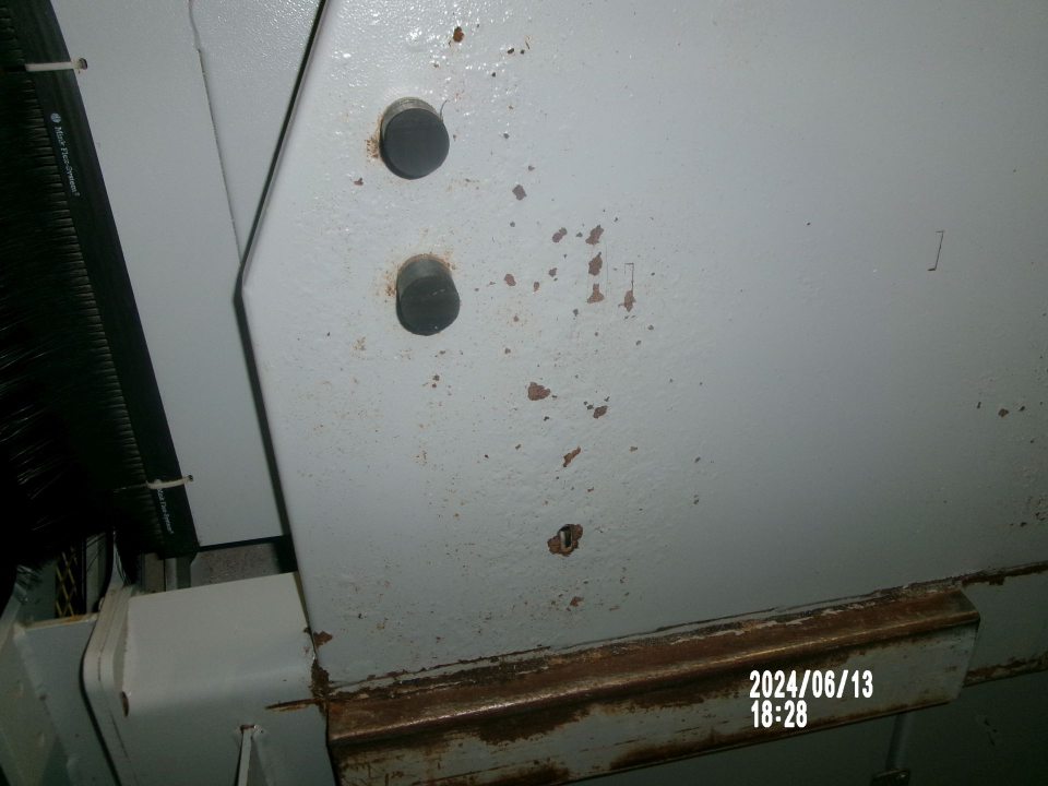  Zistený skorodovaný predný kryt lisu na papier v zázemí predajne.