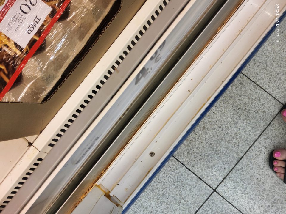 Znečistené mriežky a priestor pod mriežkou (zaschnutý vaječný obsah, vaječné škrupiny a prach) v chladiacej vitríne so zľavneným tovarom (mliečne výrobky, parené knedle, marlenka).