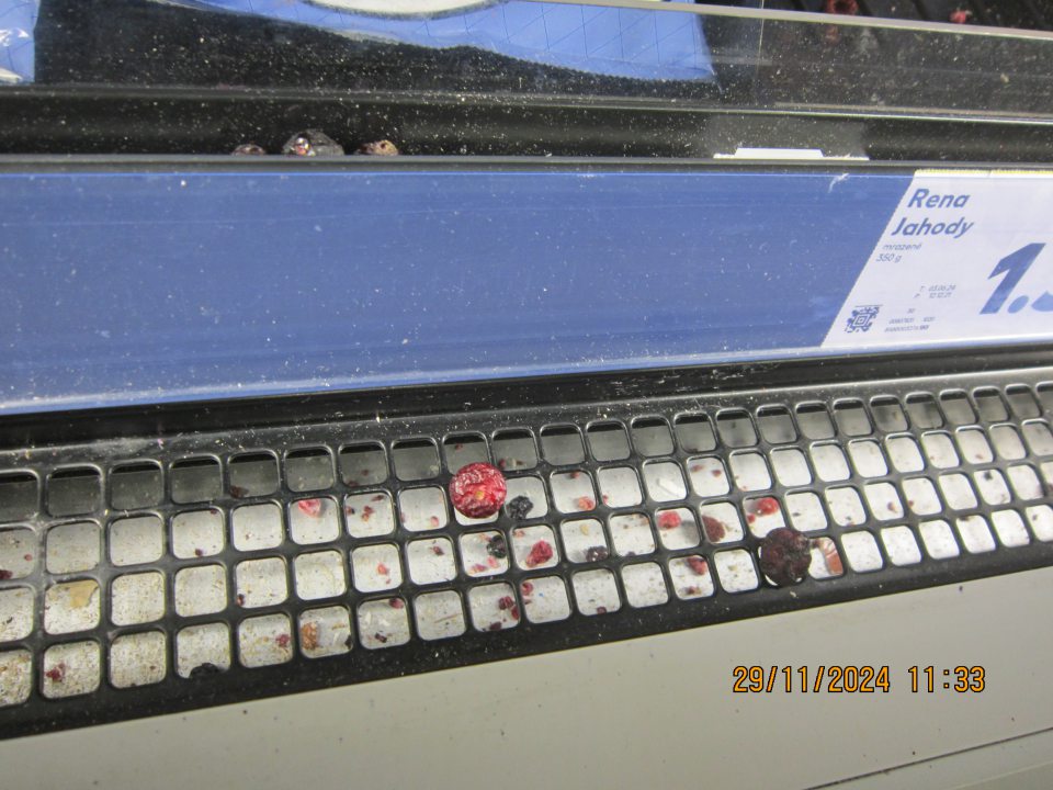 Organické nečistoty – kúsky hlbokozmrazených potravín  pod mriežkou v mraziacej vitríne na uchovávanie hlbokozmrazených potravín.