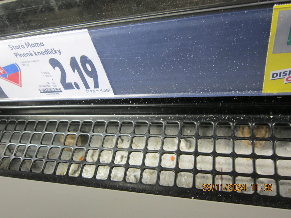 Organické nečistoty – kúsky hlbokozmrazených potravín  pod mriežkou v mraziacej vitríne na uchovávanie hlbokozmrazených potravín.