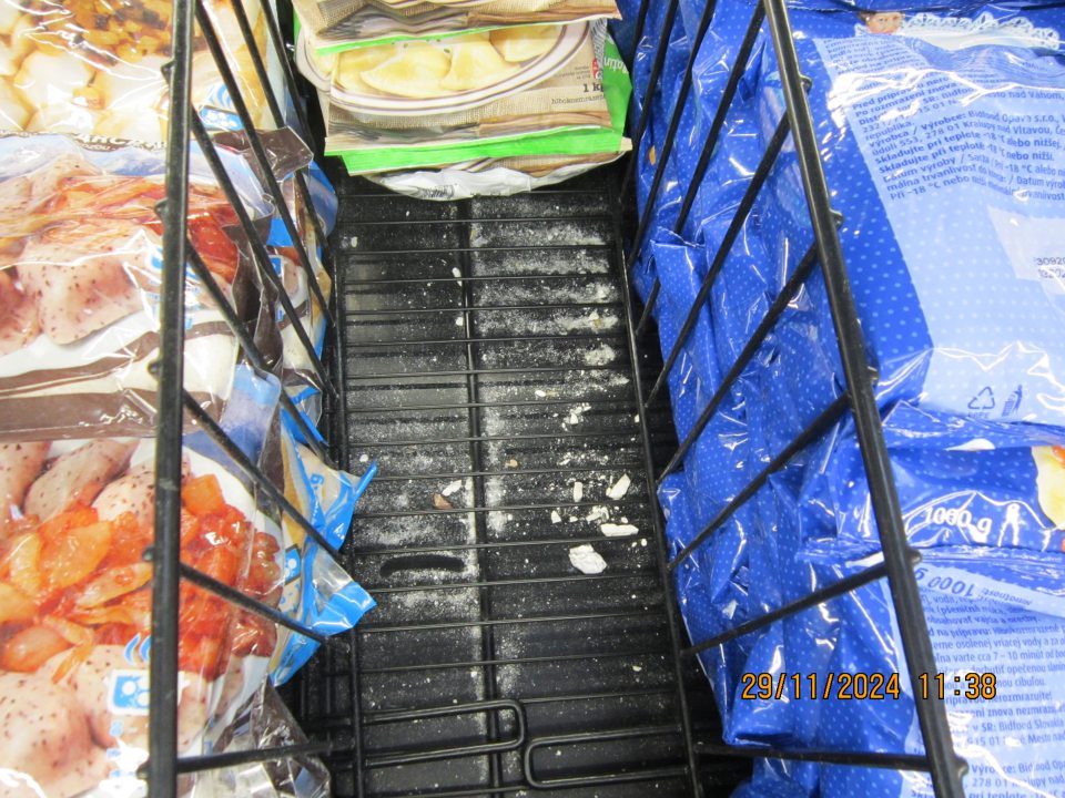 Znečistené dno mraziarenskej vane pod kovovým košom s hlbokozmrazenými pirohami múkou a úlomkami pirohov.