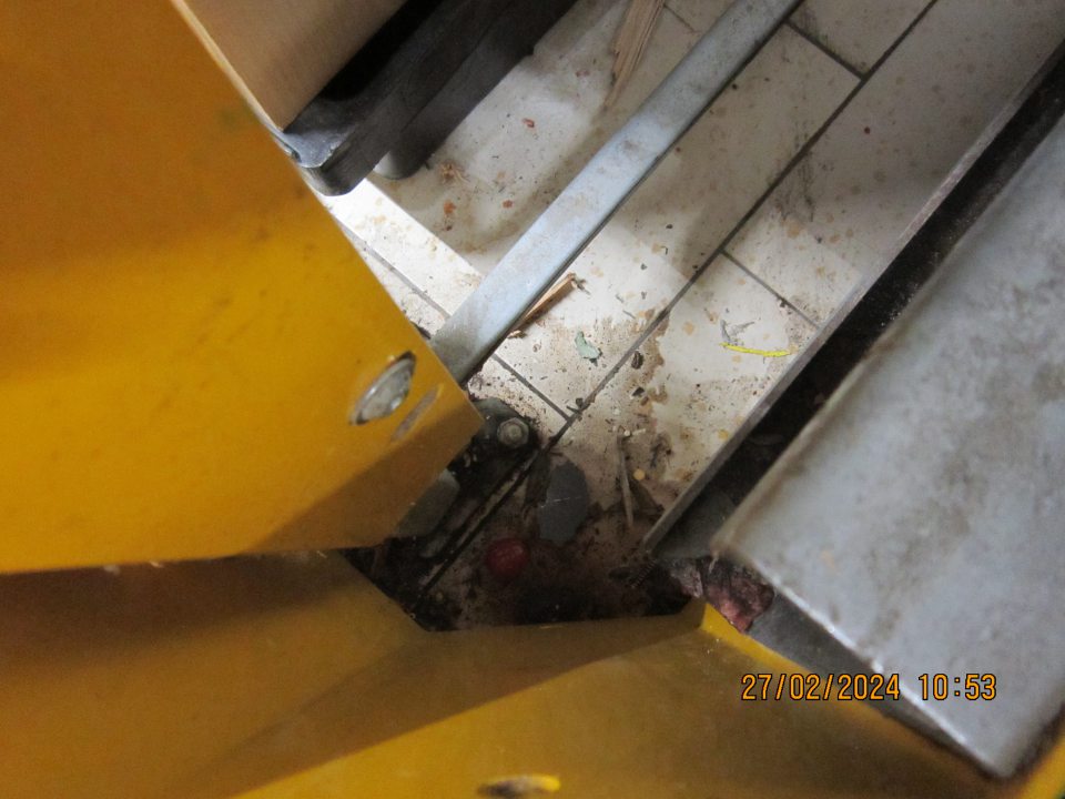 Znečistená podlaha prachom, nánosmi zaschnutej čiernej špiny, kúskami kartóna a rôznymi organickými nečistotami v priestore skladovania ovocia a zeleniny v sklade.