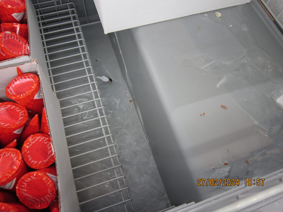 Hrubá vrstva ľadu na dne mraziaceho boxu pre uchovávanie mrazených krémov a nanukov na predajnej ploche.