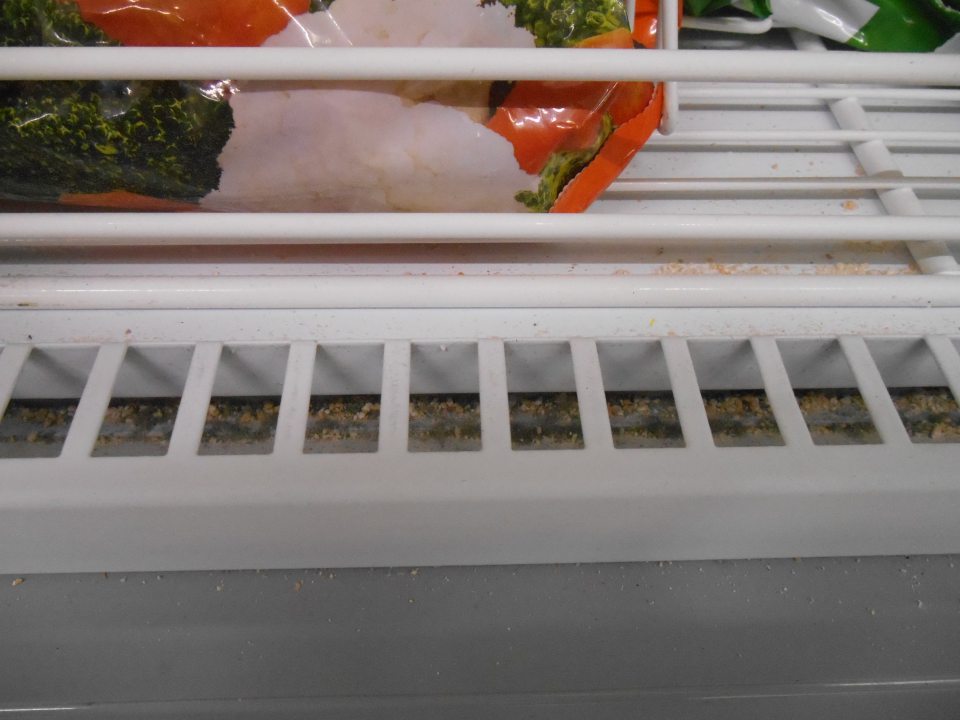 V predajnej časti prevádzky znečistené dno pod mriežkami pri otváracích dvojkrídlových dvierkach v mraziacej vitríne - prachom, organickými nečistotami, zbytkami potravín.