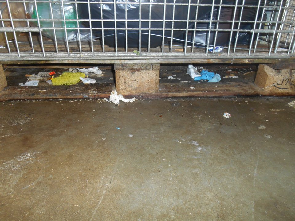Hrubé nečistoty v priestore na rampe prevádzky pod drevenou paletou, na ktorej je umiestnená klietka s odpadom.