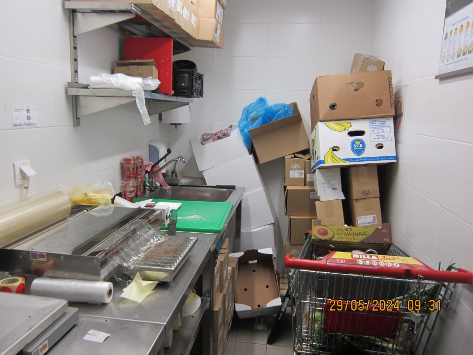 V miestnosti „Čistá príprava OZ“ v zázemí umiestnený odpis ovocia a zeleniny v nákupných vozíkoch, kartóny so sušeným ovocím a s plastovými cenovkami. Na stole sú kúsky papierikov, zbytky ovocia a zeleniny.