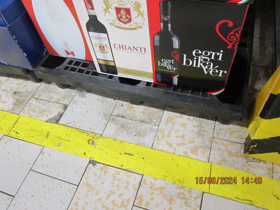 Znečistená podlaha nánosmi čiernej špiny (šmuhami) v priestore skladovania alkoholických a nealkoholických nápojov v sklade v zázemí.