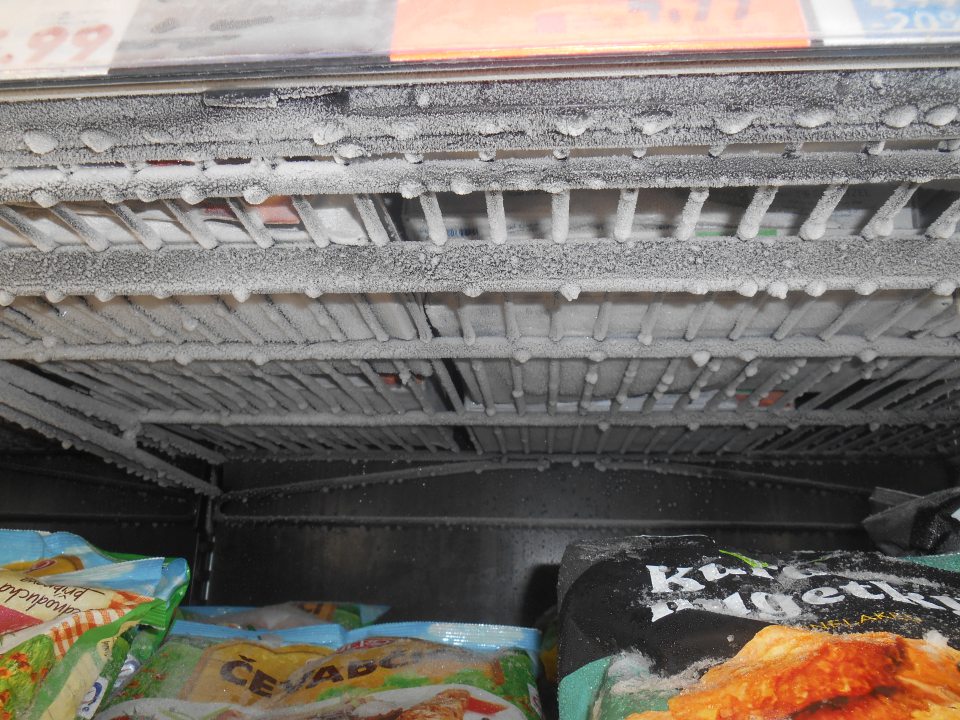 Nadmerne namrazené predeľovacie policové mriežky v mraziacej  vitríne na uchovávanie hlbokozmrazených polotovarov a hotových jedál na predajnej ploche prevádzky. 