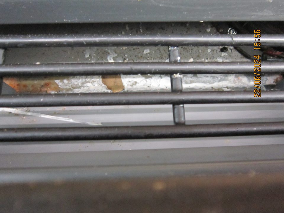 Znečistenie pod mriežkou v spodnej časti chladiarenskej vitríny určenej na uchovávanie mliečnych výrobkov a čerstvých vajec na predajnej ploche- pod vrstvou ľadu sú organické nečistoty, kúsky kartónu, zbytky potravín.