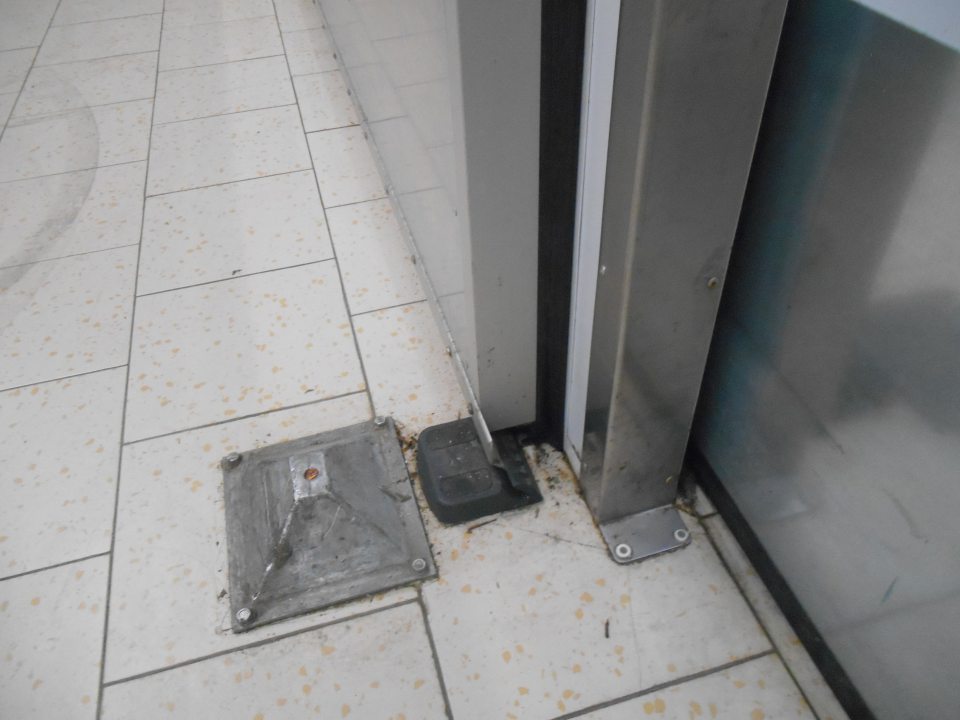 Znečistená podlaha v skladovacej časti  prevádzky pri pätkách zasúvacích dverí do chladiaceho boxu MOPRO 1 prachom, drobnými kúskami rôznych nečistôt.