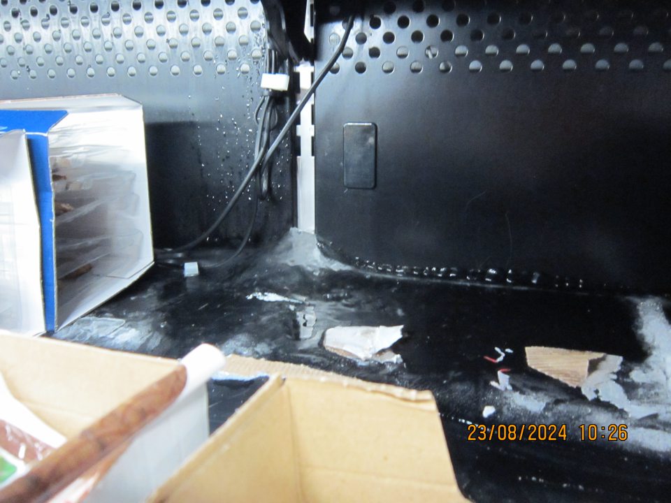 Nadmerná námraza a zamrznuté kúsky kartónu na dne chladiacej vitríny na uchovávanie rybacích výrobkov na predajnej ploche.