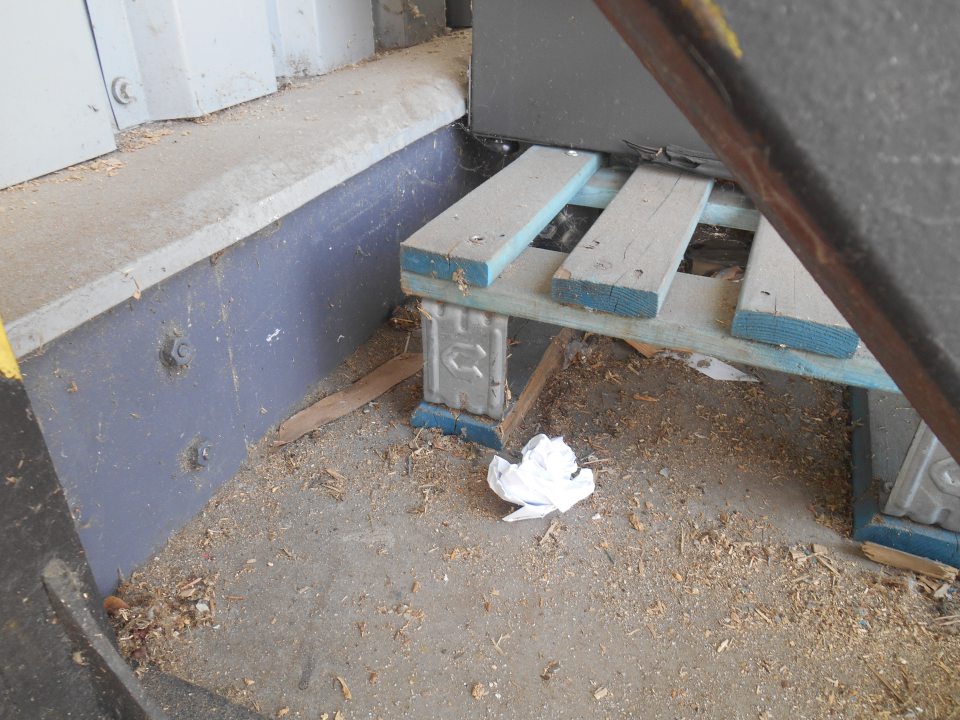 Hrubé nečistoty- špina, prach, kúsky kartónov, útržky papiera a drevené triesky  pod paletami s vyradeným chladiacim zariadením umiestneným vo vonkajšom prostredí v tesnej blízkosti príjmovej rampy. 