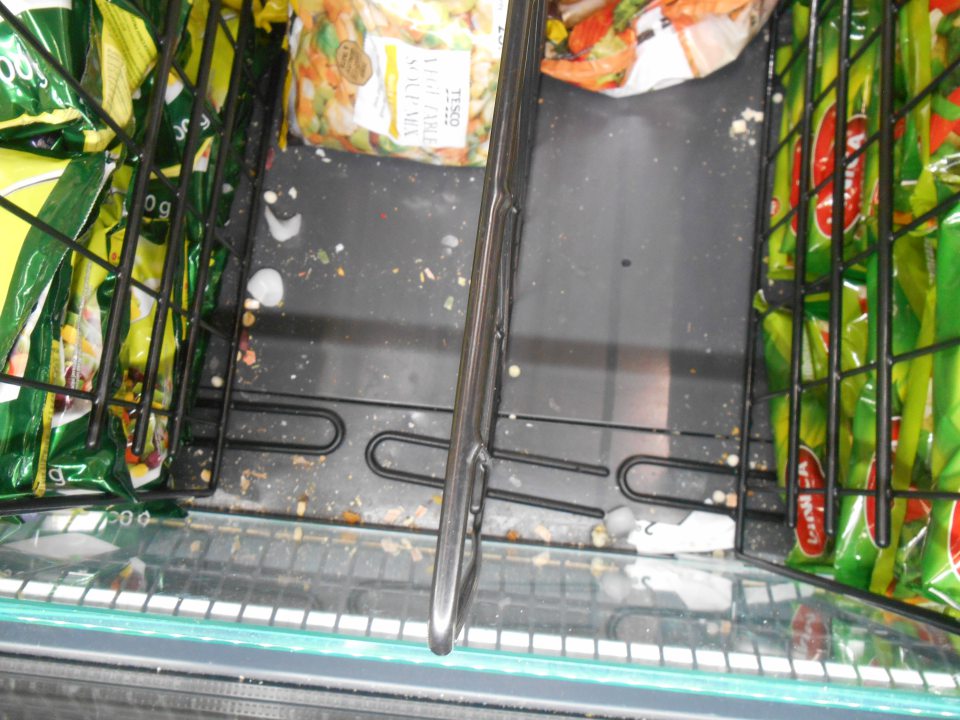 V mraziarenskom zariadení na predajnej ploche silne znečistené dno zbytkami rozsypaného tovaru, kúskami ľadu a škrupinami z pistácií.