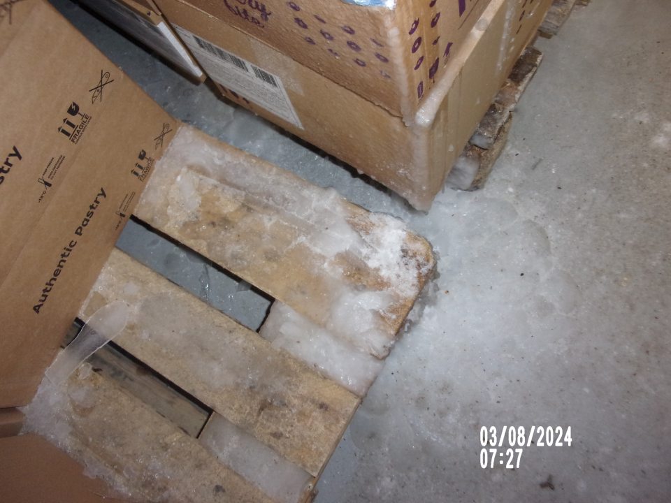 Namrznutý ľadový povlak na podlahe, výrobkoch v mraziacom boxe v zázemí.