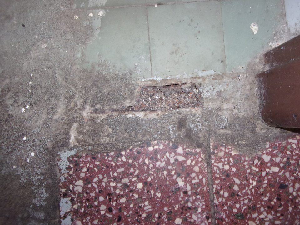 Poškodená podlaha v prechode zo skladu potravín do skladu čistiacich prostriedkov.