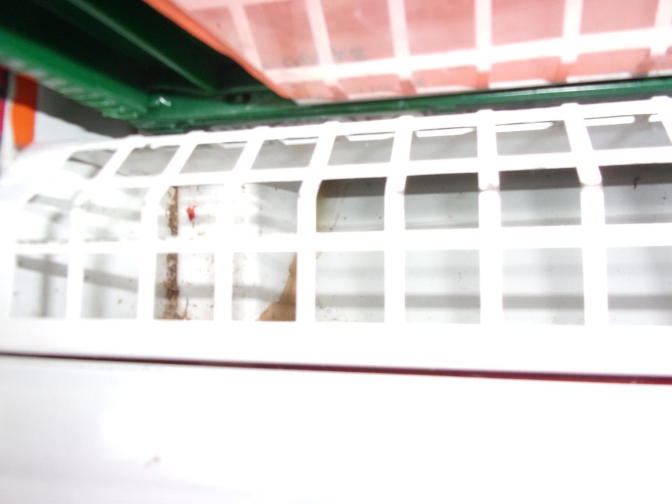 Znečistený priestor pod mriežkou vo vitríne na zeleninu.