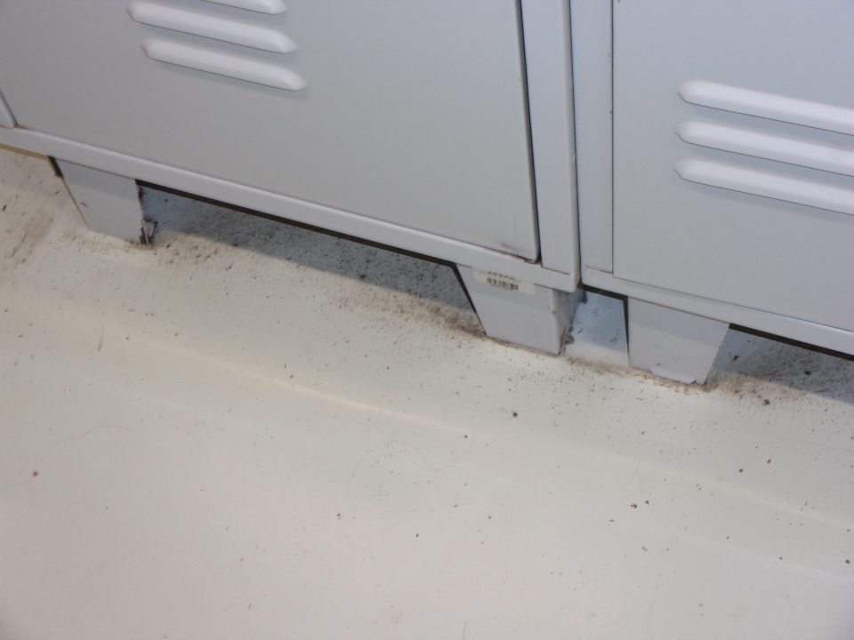 Znečistená podlaha v šatni pod skrinkami zamestnancov.