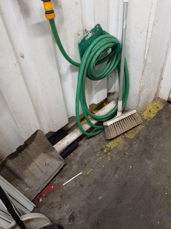 pri príjmovej rampe okolo dverí znečistená podlaha, voľne položené náradie na upratovanie