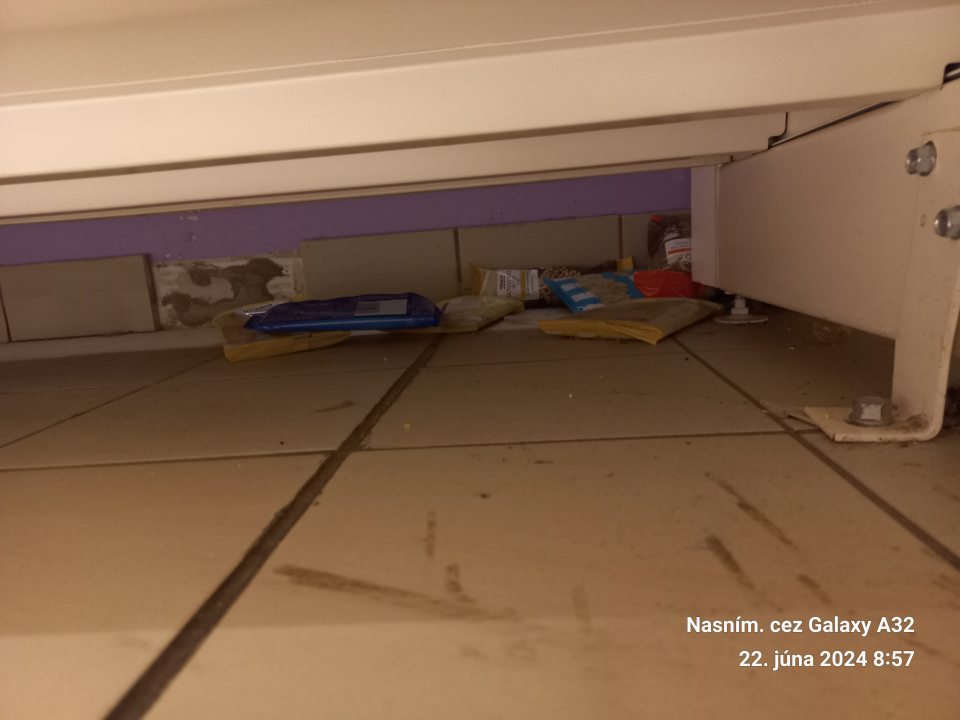 Znečistená podlaha na predajnej ploche pod všetkými regálmi s potravinami - vrstva prachu, popadaný tovar.