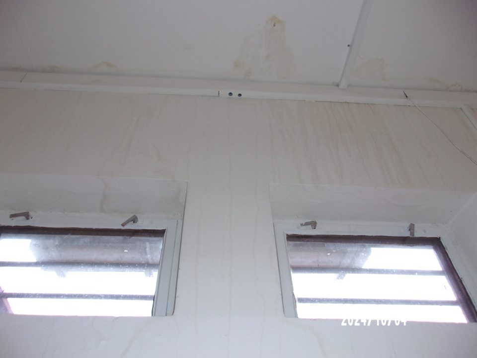 Stena a strop nad chladiacimi vitrínami na vystavovanie mliečnych výrobkov a nad regálom s nebaleným pečivom poškodené zatečením.