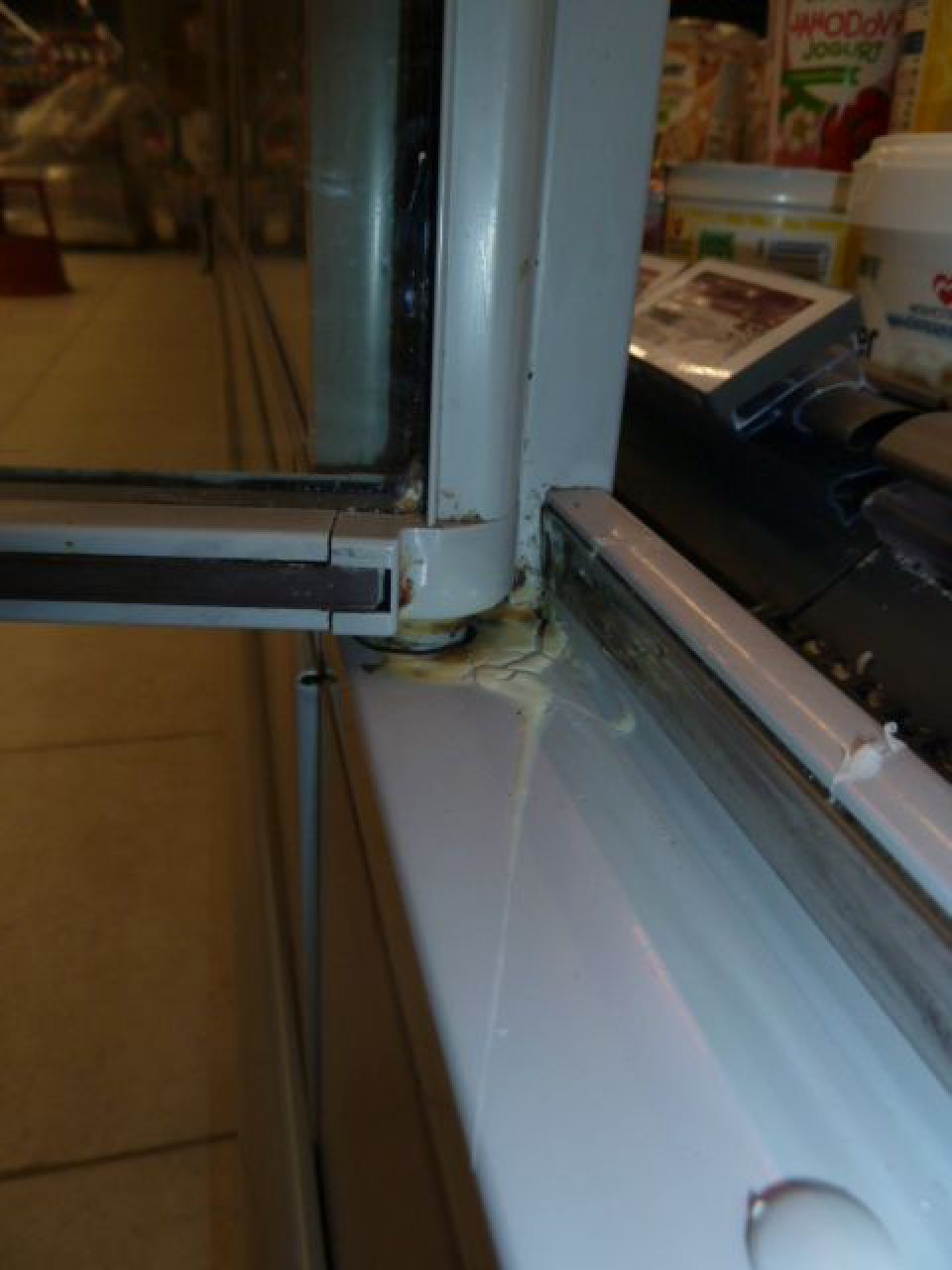 Dvere chladiaceho zariadenia  na predaj mlieka a mliečnych výrobkov  boli znečistené  zaschnutou tekutinou.