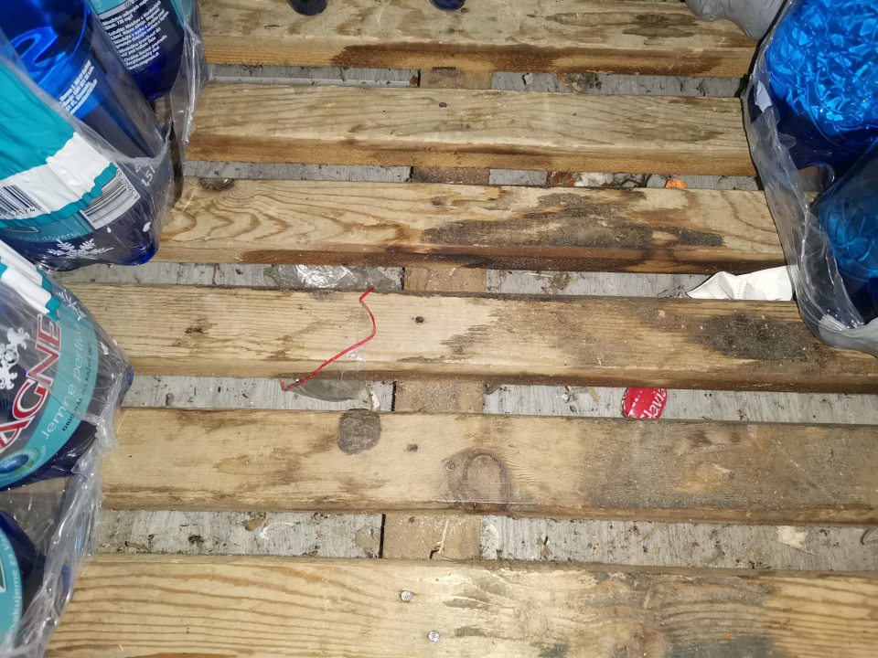Znečistená podlaha v skladovej časti prevádzkarne pod regálovými systémami a paletovými drevenými podlažkami.