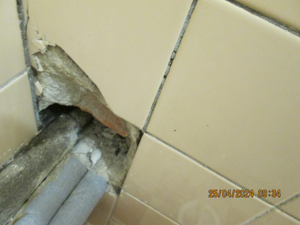 vybitá omietka steny vo WC na dvoch miestach okolo vedeného potrubia