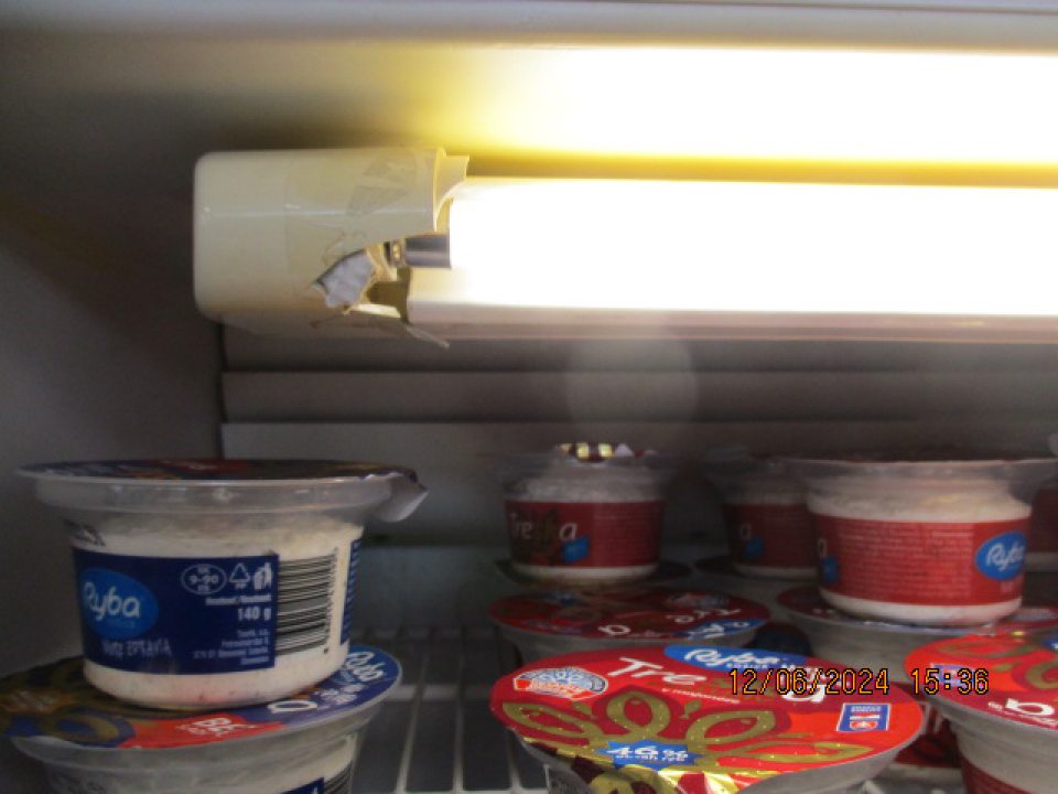 Poškodený bočný kryt osvetľovacieho zariadenia v chladiacom zariadení slúžiacom na uloženie šalátov a spracovaného ovocia a zeleniny, zadná stena chladiaceho zariadenia výskyt hrubej vrstvy námrazy.