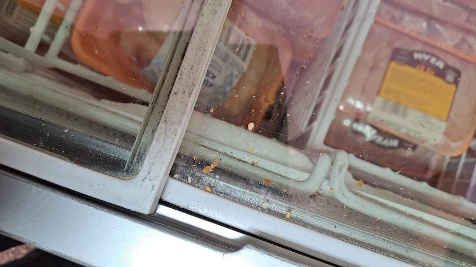 5. Znečistené mraziace zariadenie v predajni na hlbokozmrazené potraviny - povrch a lišty posuvných dvierok zbytkami potravín a nečistotami, prachom.