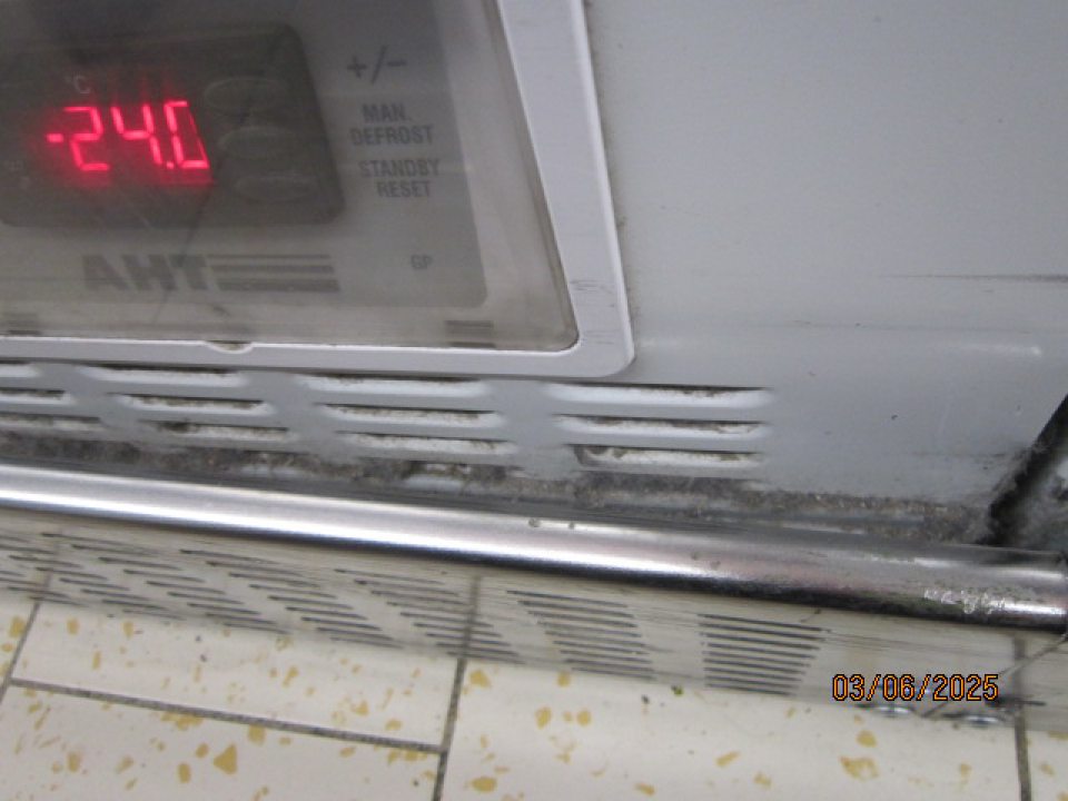 Pod kovovou lištou v spodnej časti mraziacich vitrín sa nachádzajú nečistoty, smeti, špina.