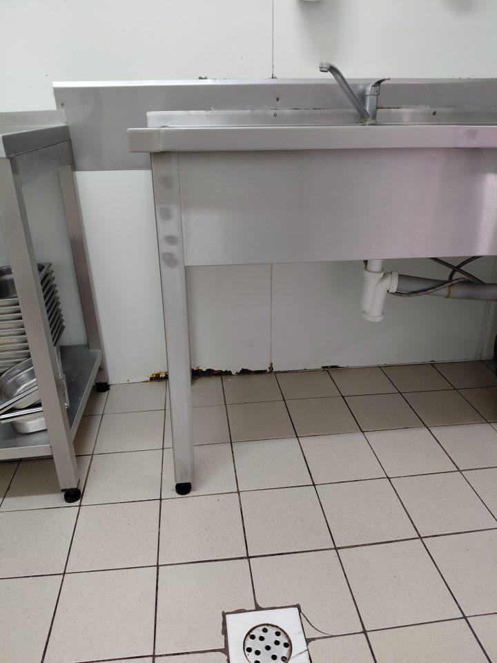 v skladovacích priestoroch v prípravovni údenín poškodený povrch steny pod umývadlom , hrdzavý, olupujúci sa náter