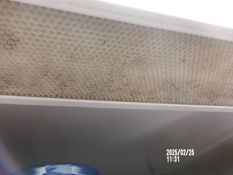Zistená znečistená vrchná plastová mriežka chladiarenskej vitríny s uchovávanými mliečnymi výrobkami. 
