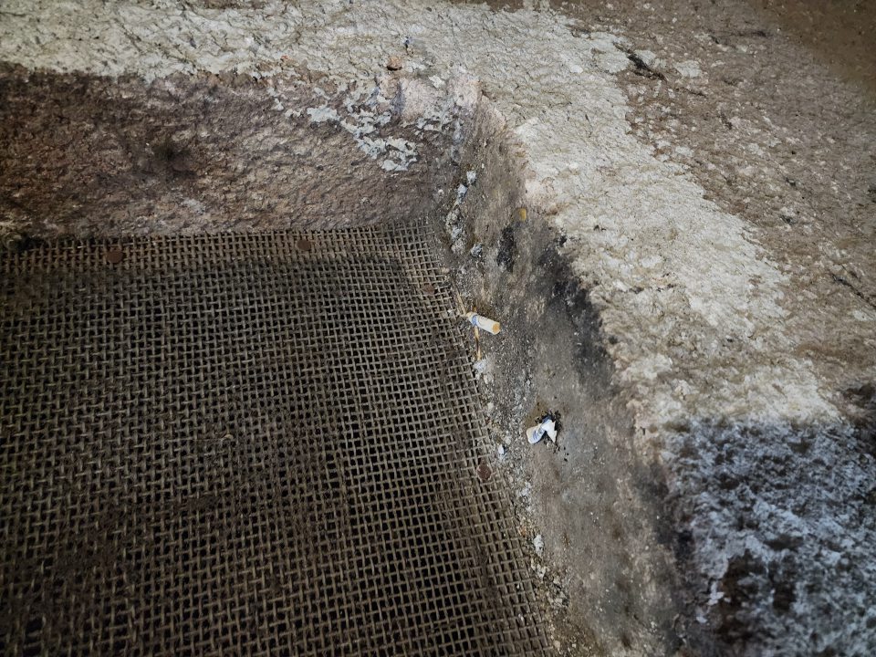 Vo výklenku na stene vedľa dverí sa nachádzajú ohorky z cigariet.