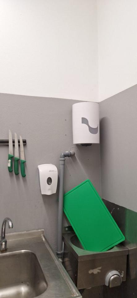 Plastová doska na mechanickú úpravu dyne umiestnená v umývadle, držiak na papierové utierky prázdny.