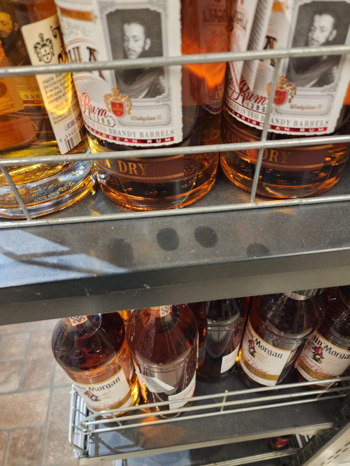 Regál s alkoholom silne znečistený vrstvou prachu.