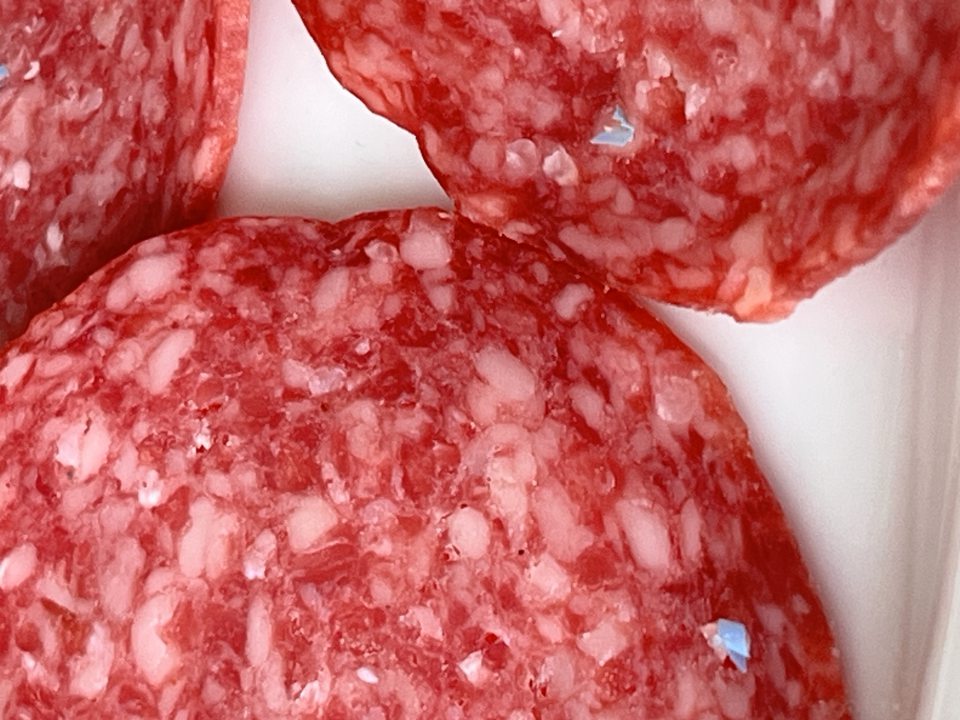 Výskyt drobných kúskov plastu v náreze salámy.