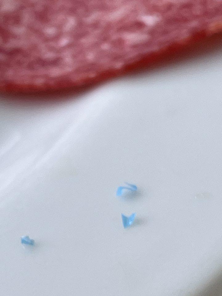 Drobné kúsky plastu pochádzajúce z nárezu mäsového výrobku.