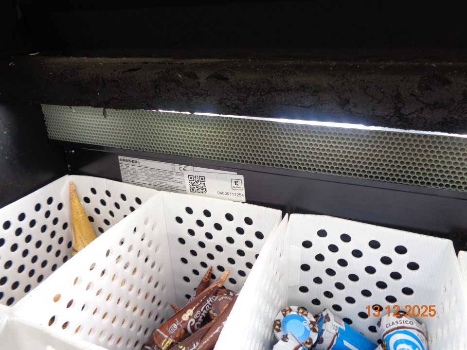 Rozpadávajúca sa izolačná pena proti vytváraniu námrazy v priestore pod posuvnými dvierkami v mraziacom boxe na uchovávanie nanukov  na predajnej ploche prevádzky.