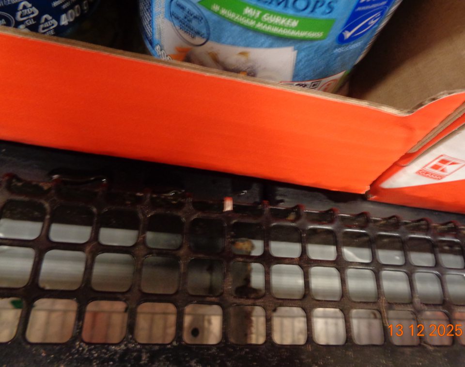 Kovové mriežky chladiaceho zariadenia na uchovávanie chladených spotrebiteľsky balených lahôdkarských výrobkov a rybacích šalátov znečistené usadenými nečistotami a prachom na predajnej ploche prevádzky.