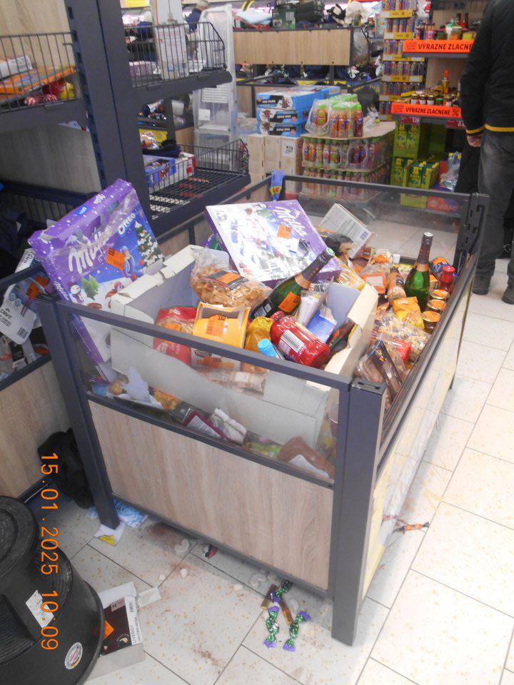 Na predajnej ploche pod prepravným košom na zľavnený tovar – celé kúsky a zbytky tuhých a vytečených tekutých potravín, kúsky obalových materiálov, rozsypané balenia cukroviniek, sypkého tovaru (kakao) a tovaru z regálu non food (ponožky, tričká).